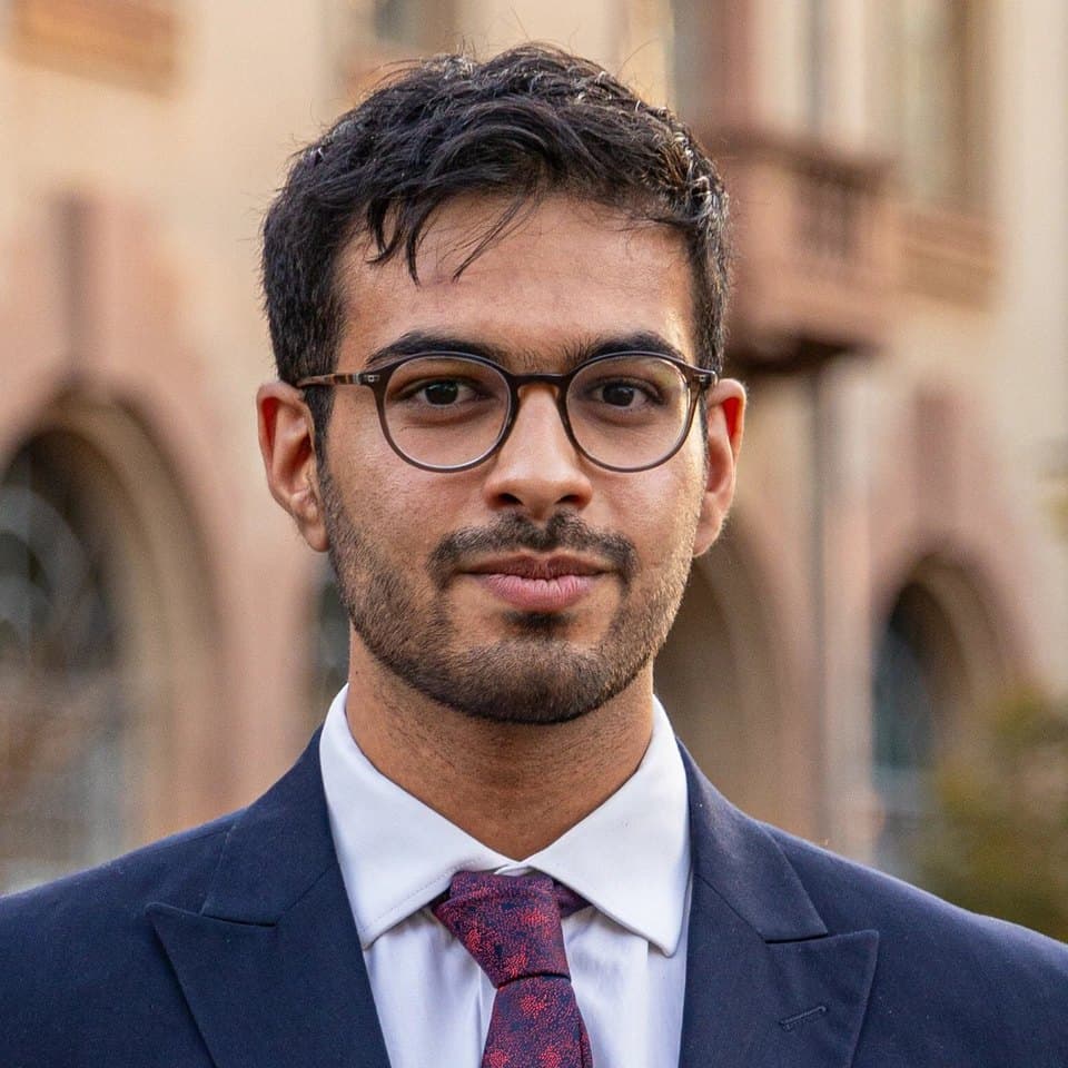 Talhah Patelia in a navy suit and tie, outdoors